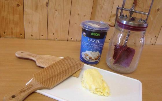 A pot of cream and mixer on a wooden table ready for the butter making workshop
