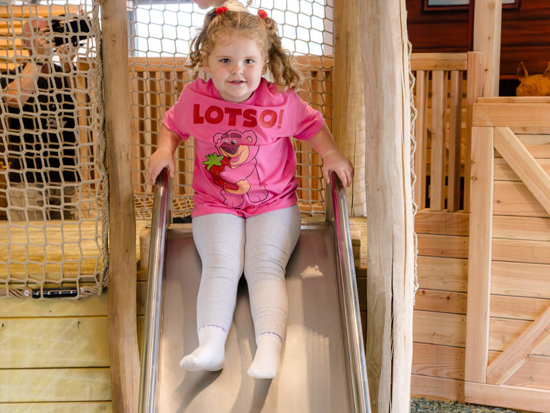 Young girl enjoying the slide in the indoor adventure play at Greenmeadow Community Farm