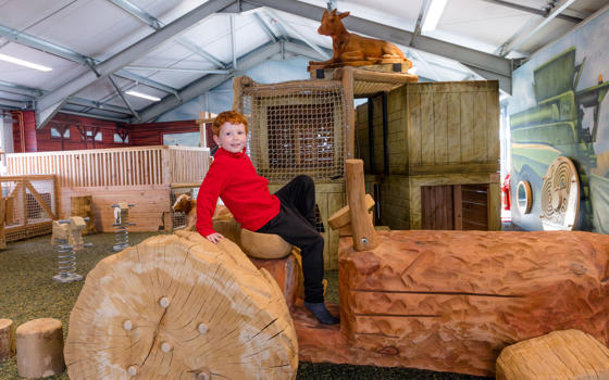 Young boy sitting on a wooden tractor in the indoor adventure play